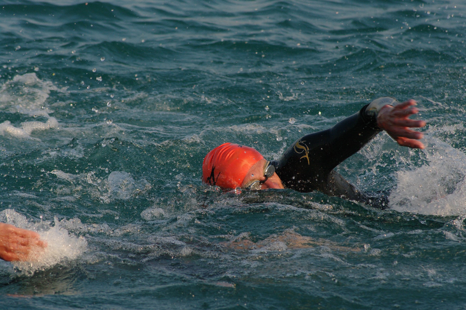 A lone triathlete swimming through open water at an Ironman race